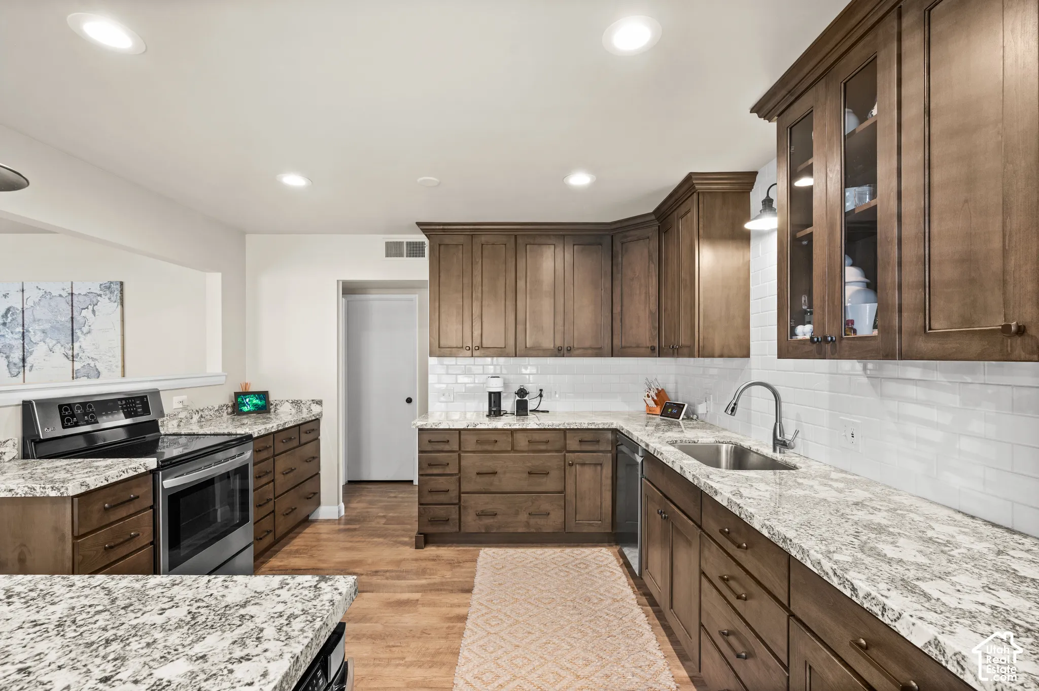 Kitchen featuring stained wood cabinetry, stone-surface countertops, white subway tile backsplash, recessed lighting, and stainless steel appliances