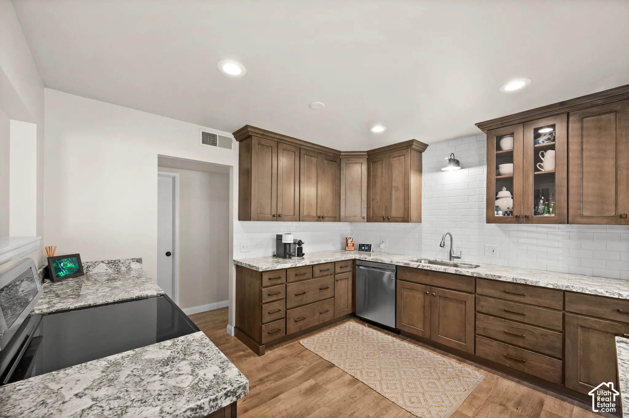Kitchen featuring custom wood cabinetry, stone countertops, white subway tile backsplash, stainless steel appliances, and recessed lighting