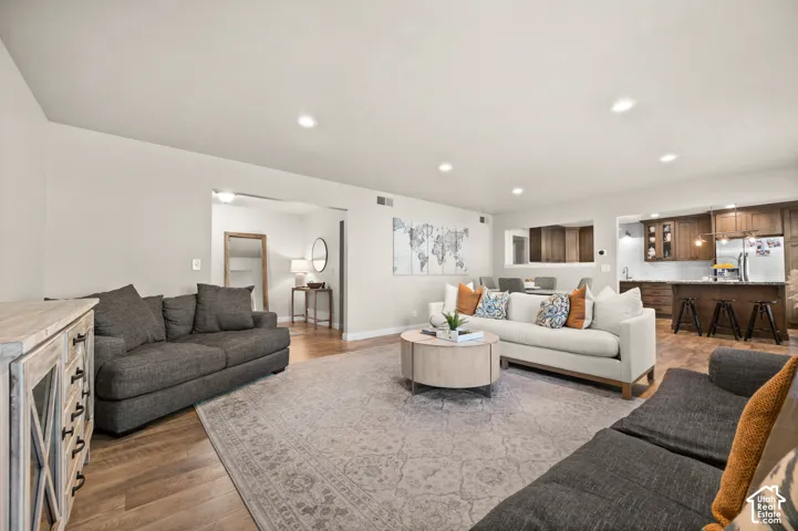 Open interior featuring wood-finish flooring, recessed lighting, and a kitchen peninsula with bar-style seating
