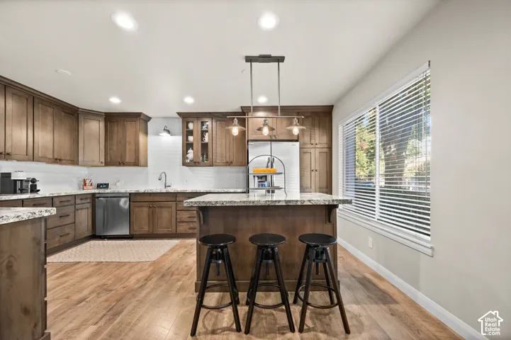 Kitchen featuring wood cabinetry, stone countertops, wood-finish flooring, recessed lighting, and a pendant-lit center island