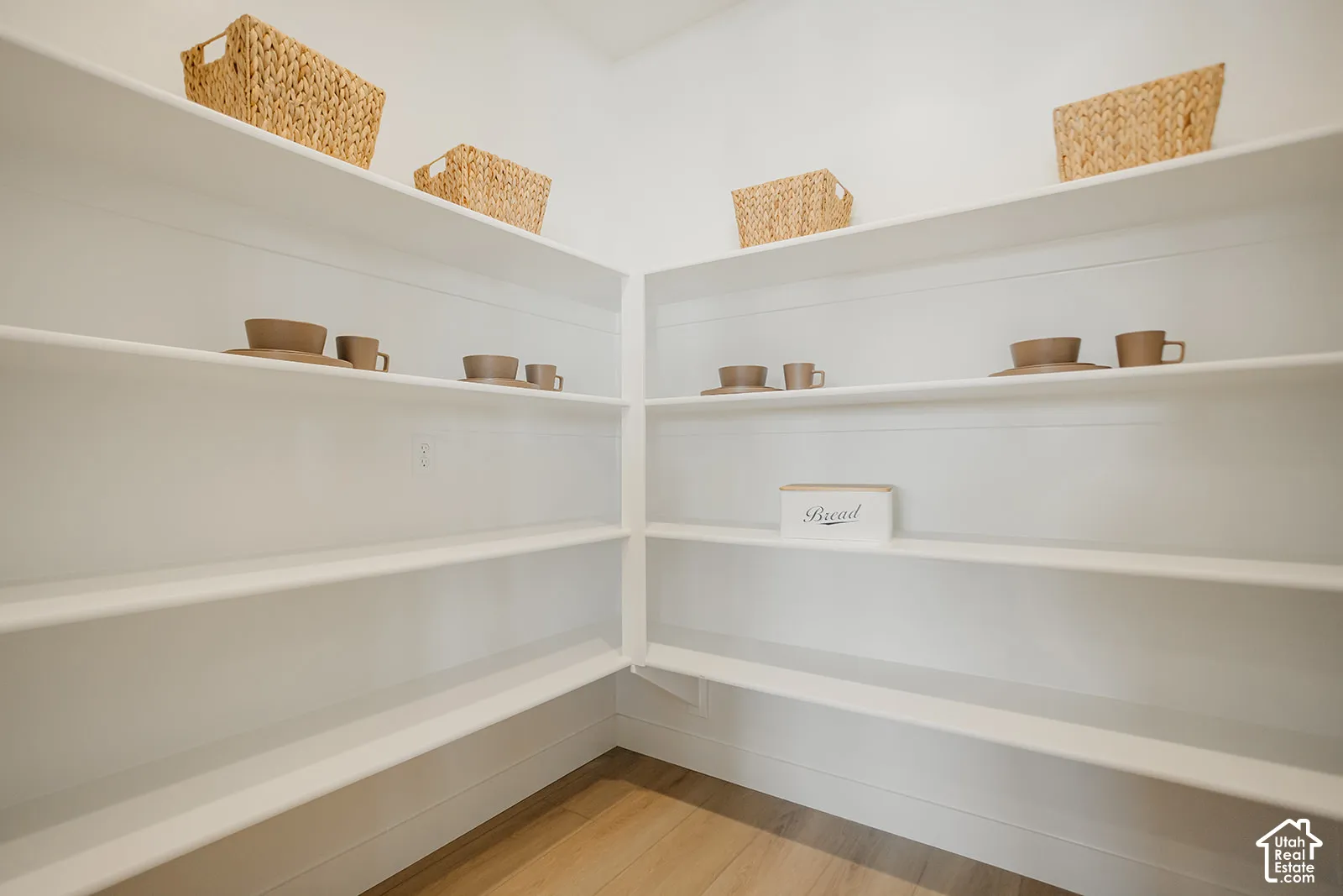 Walk-in pantry featuring white wrap-around shelving and wood-finish flooring