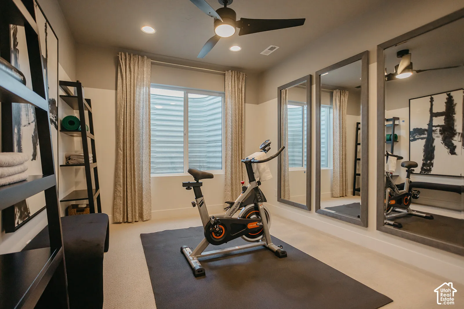 Room featuring neutral wall-to-wall carpeting, recessed ceiling lighting, a matte black ceiling fan, and full-length wall-mounted mirrors with dark-toned frames