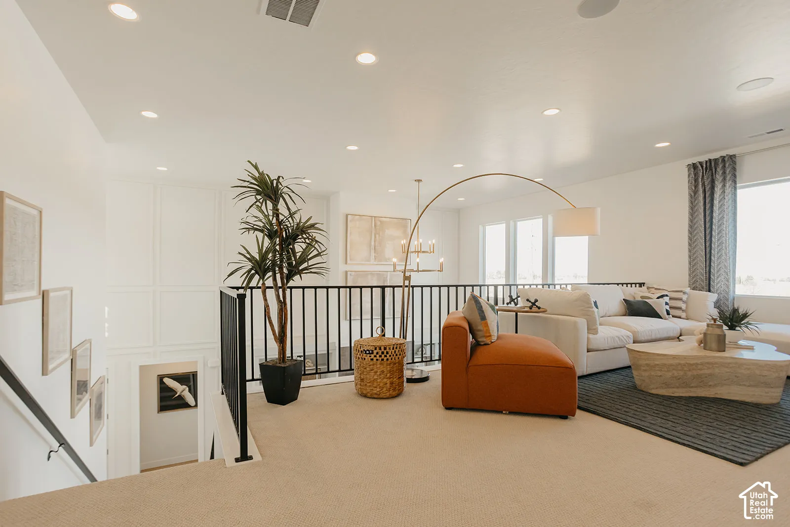 Open loft area featuring recessed lighting, paneled wall detailing, and a black metal railing
