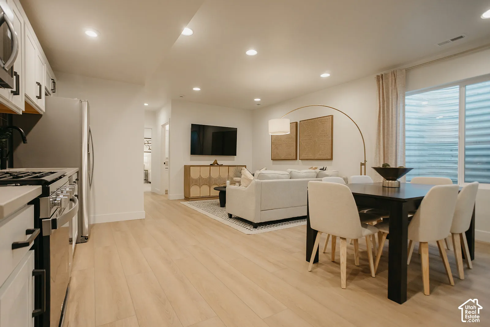 Open-concept living space featuring wood-finish flooring, recessed lighting, and white cabinetry