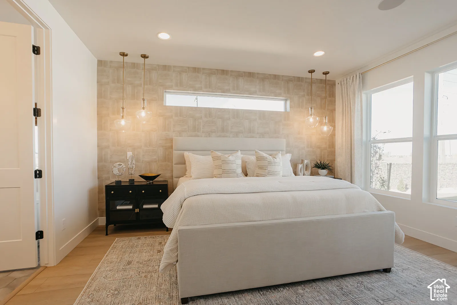 Textured accent wall featuring a rectangular clerestory window, integrated pendant lighting, and light-toned wood-finish flooring