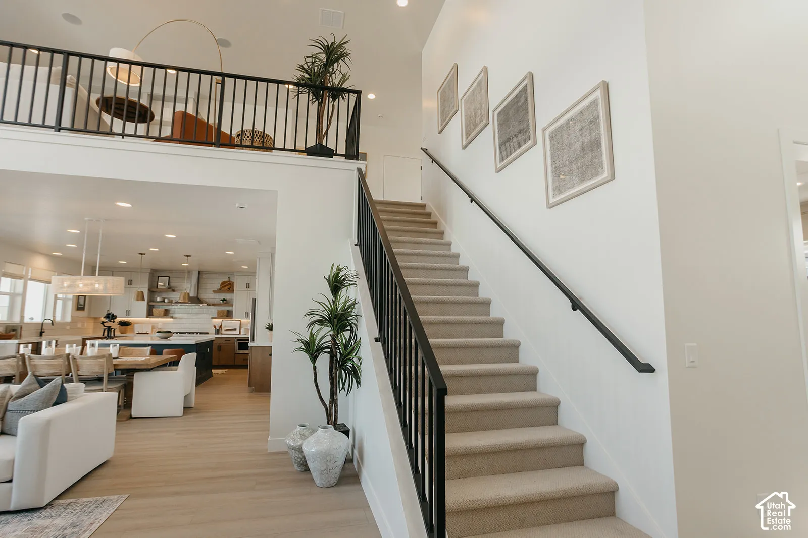 Two-story foyer featuring a carpeted staircase with a matte black metal railing, overhead recessed lighting, and wood-finish flooring