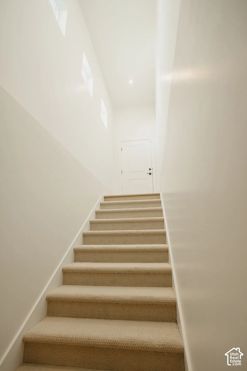 Staircase featuring neutral carpeting, high ceilings, recessed lighting, and multiple clerestory windows