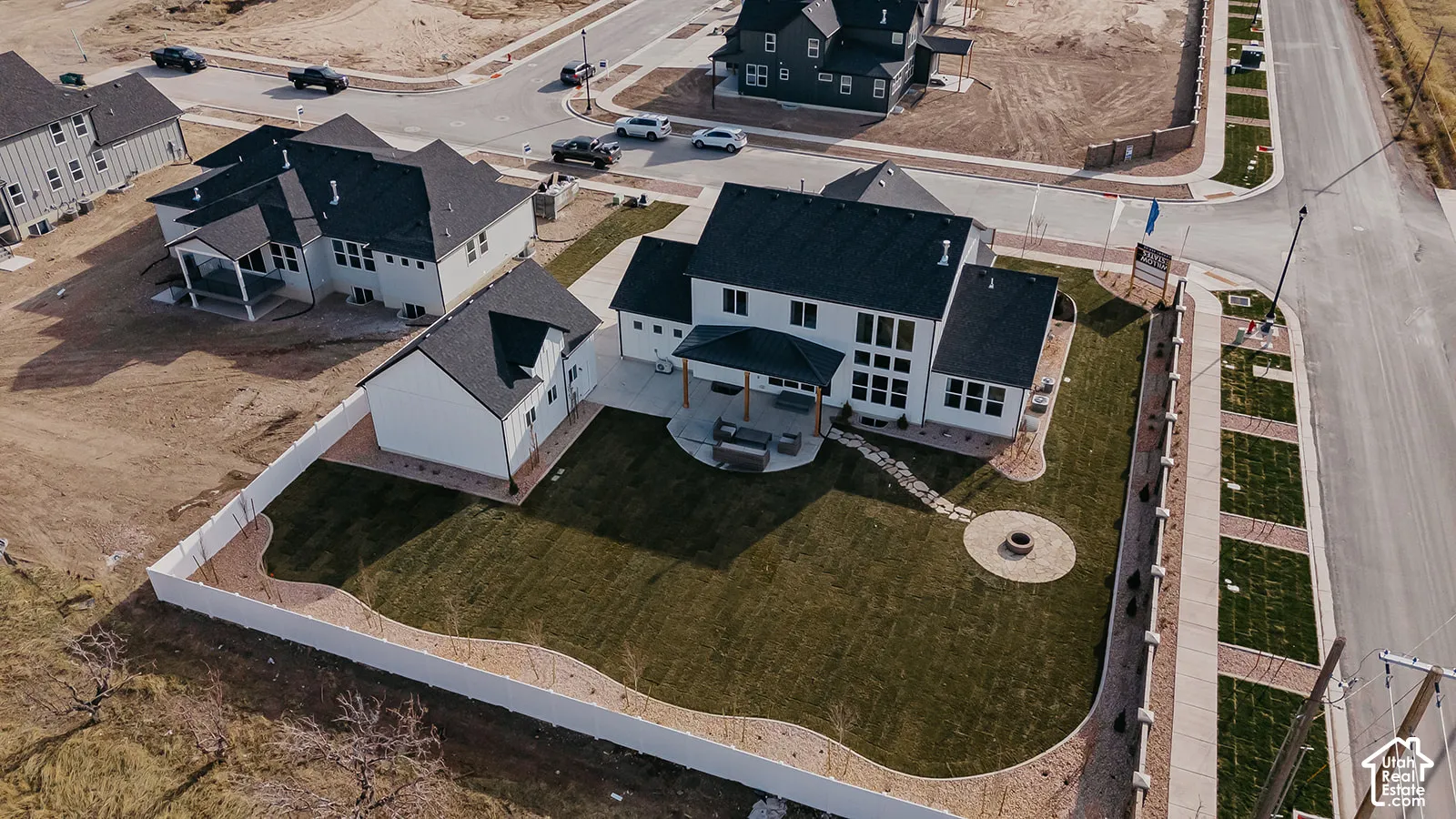 Corner lot featuring a fenced backyard, covered rear patio, integrated fire pit, and professional landscaping