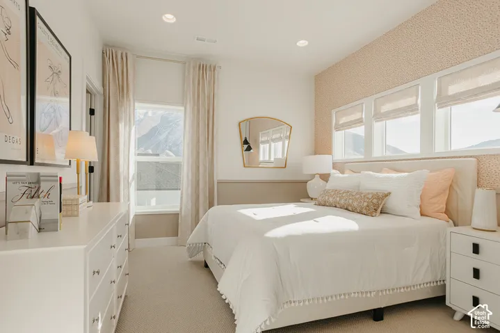 Bedroom featuring textured wall treatments, recessed lighting, neutral carpeting, and a series of windows