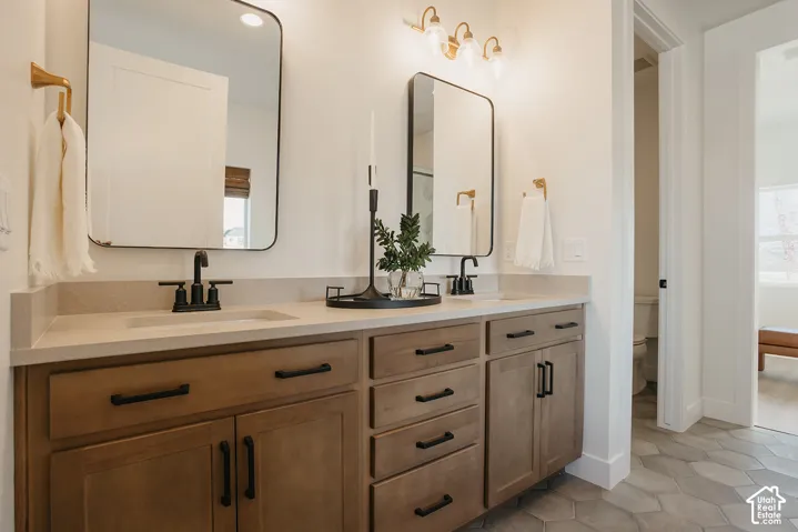 Double vanity featuring wood-finish cabinetry, quartz countertops, dual rectangular sinks with matte black faucets, and hexagonal tile flooring