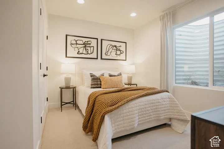 Neutral-toned carpeted flooring, recessed lighting, and a large egress window with a corrugated window well