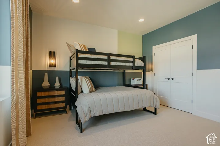 Room featuring neutral carpeting, double-panel closet doors with matte black hardware, recessed ceiling lighting, and wall-mounted sconce lighting