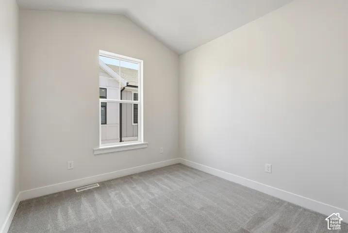 Vaulted ceiling, neutral wall tones, wall-to-wall carpeting, and a single-hung window with a grid pattern