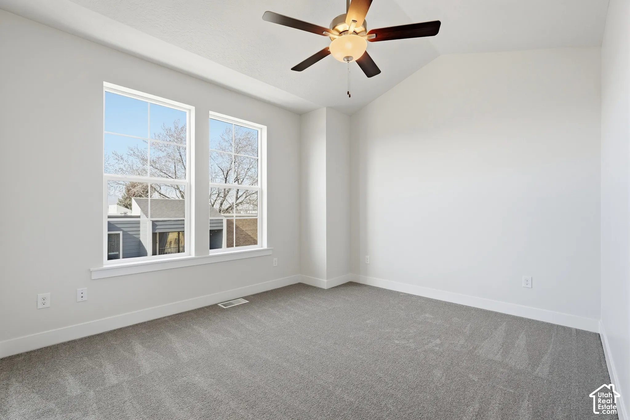 Vaulted ceiling with a centrally mounted dual-finish ceiling fan, neutral wall-to-wall carpeting, and double-pane windows