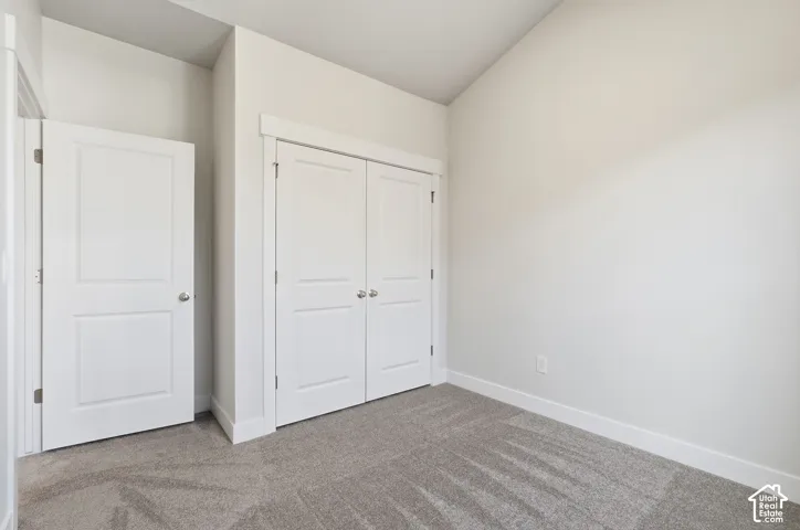 Vaulted ceiling, neutral wall tones, carpeted flooring, and white paneled doors