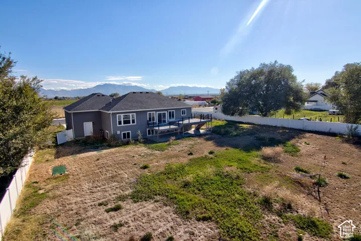 Expansive exterior lot featuring a raised rear deck, mountain backdrop, and privacy fencing