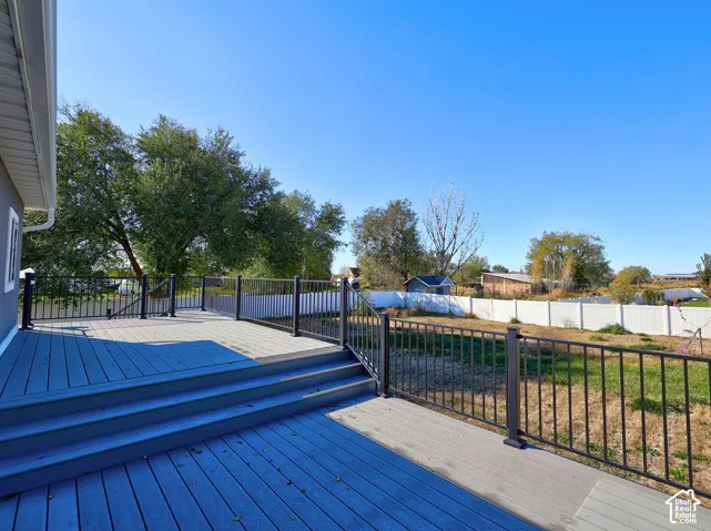 Multi-level composite deck featuring metal railings and stairs leading to a fenced backyard