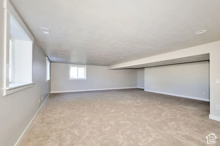 Expansive room featuring wall-to-wall carpeting, neutral-toned paint, recessed lighting, and multiple windows