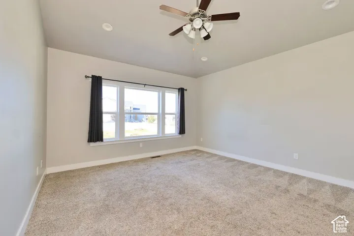 Neutral-toned interior room featuring carpeted flooring, a multi-light ceiling fan, recessed lighting, and a multi-pane window