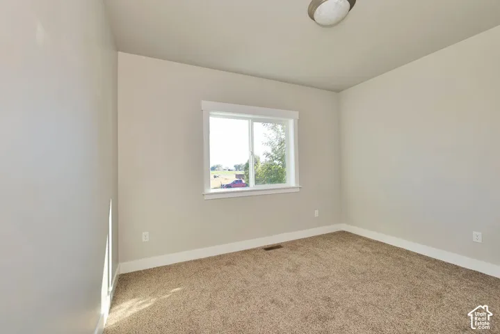 Neutral-toned room featuring wall-to-wall carpeting, a horizontal sliding window with white trim, and a dome-style flush-mount ceiling light