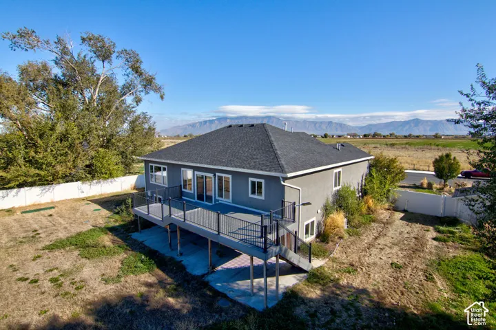 Exterior featuring grey stucco siding, an elevated deck with metal railings, and mountain scenery