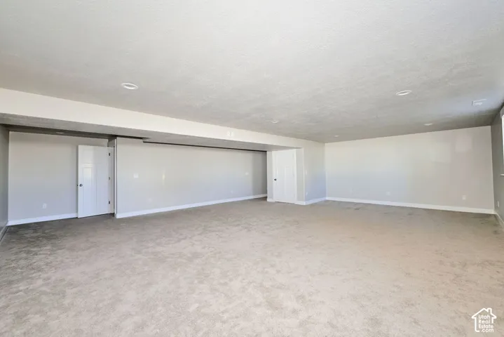 Expansive interior space featuring neutral wall tones, wall-to-wall carpeting, recessed ceiling lighting, and two interior doors