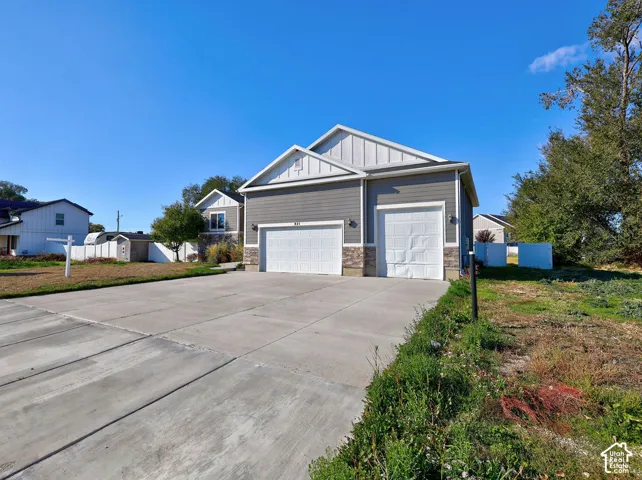 Exterior featuring horizontal lap siding, stone veneer accents, a concrete driveway, and a three-car garage with white paneled doors