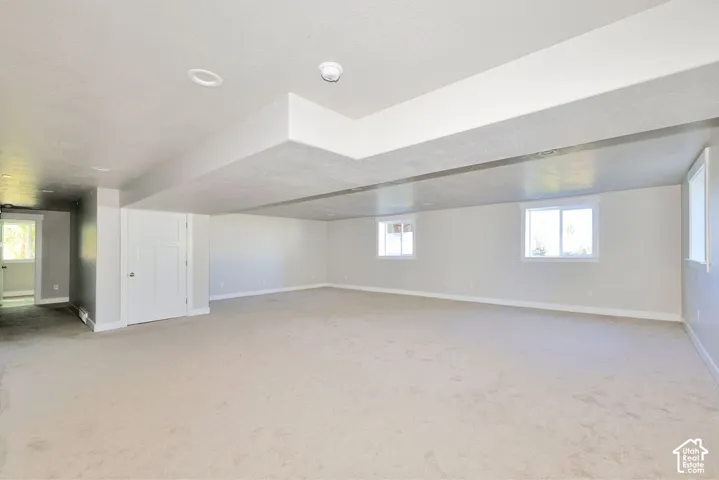 Neutral-toned carpeting, recessed ceiling lighting, and multiple windows