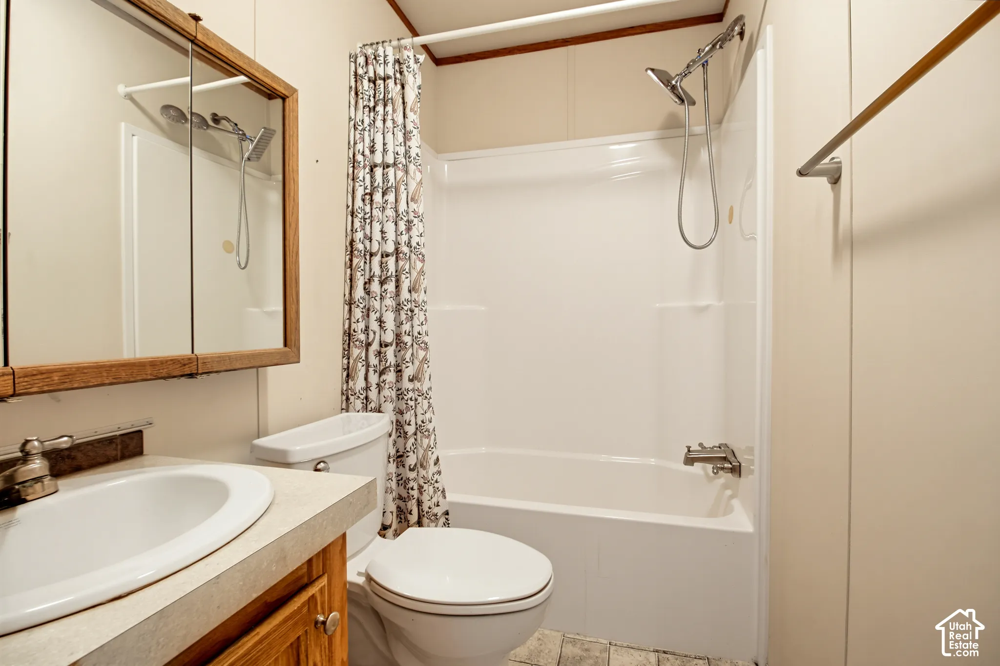Bathroom featuring a composite vanity with an integrated sink, wooden medicine cabinet, bathtub with a white surround, and a flexible-hose showerhead