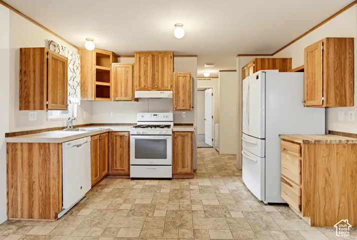 Kitchen featuring natural wood-finish cabinetry, solid-surface countertops, tile-patterned flooring, and white kitchen appliances