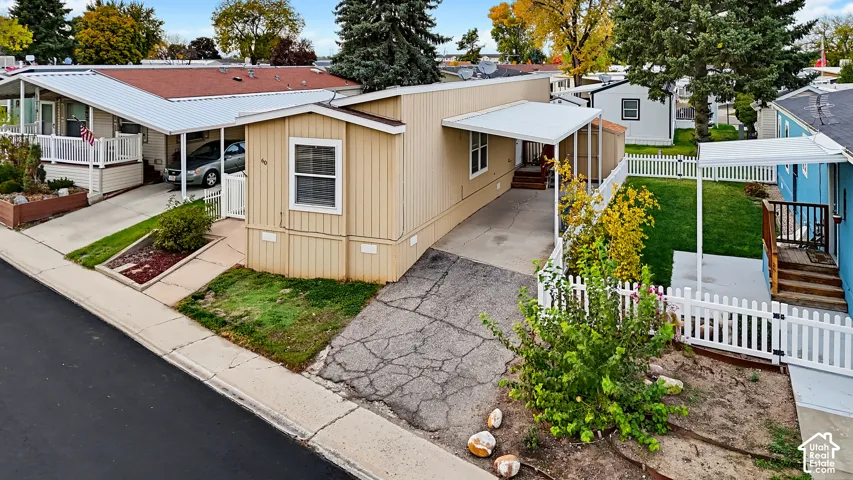 Single-level residence featuring vertical siding, an attached metal carport, and a white picket fence enclosure