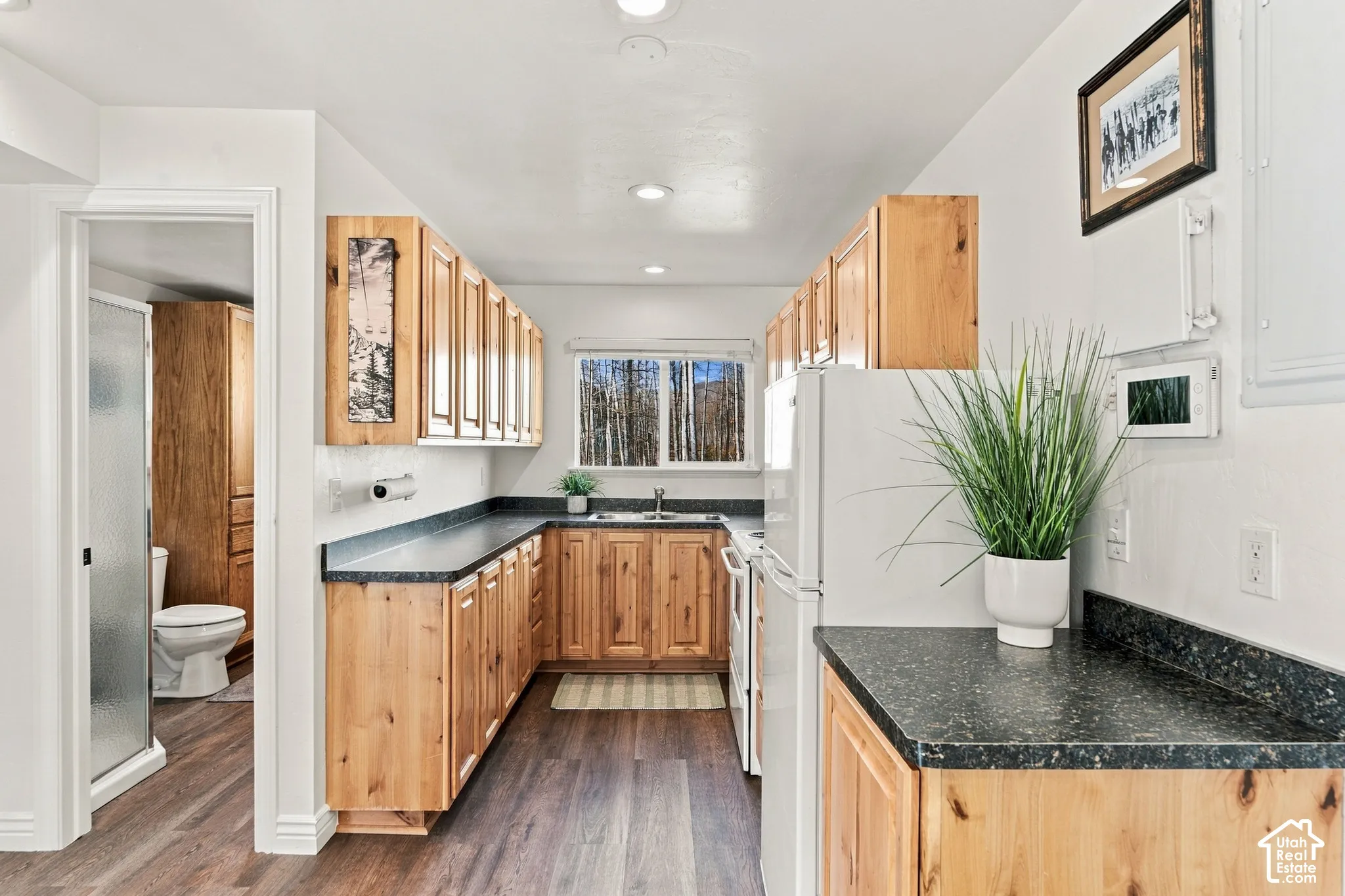 Kitchen featuring wood cabinetry, dark stone-finish countertops, wood-finish flooring, and recessed lighting