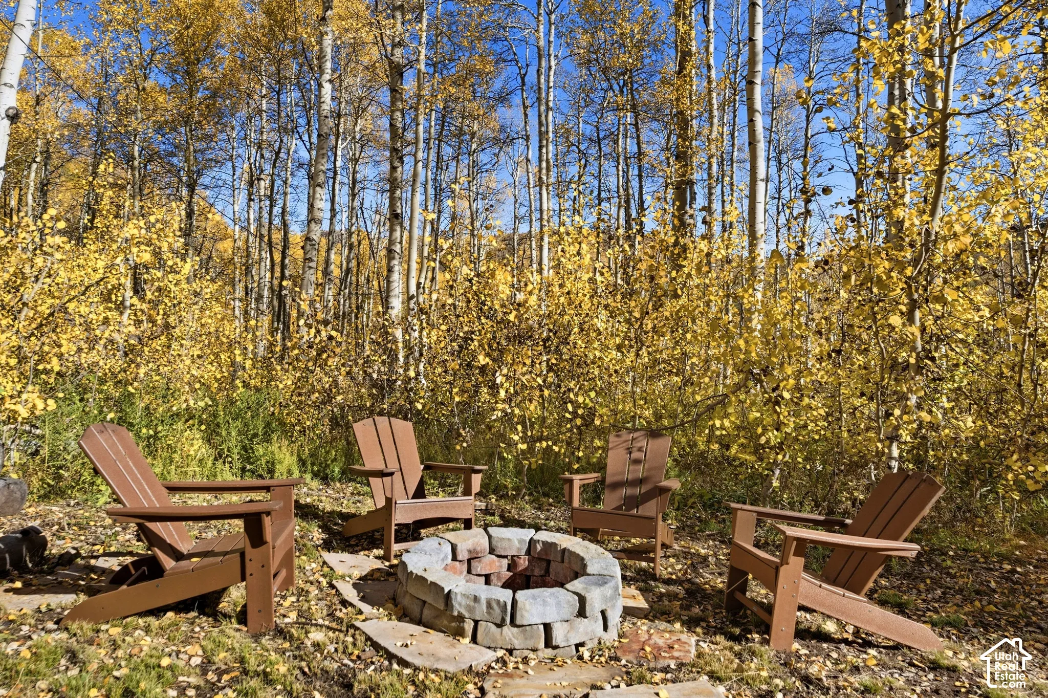 Stacked-stone fire pit surrounded by mature aspen trees