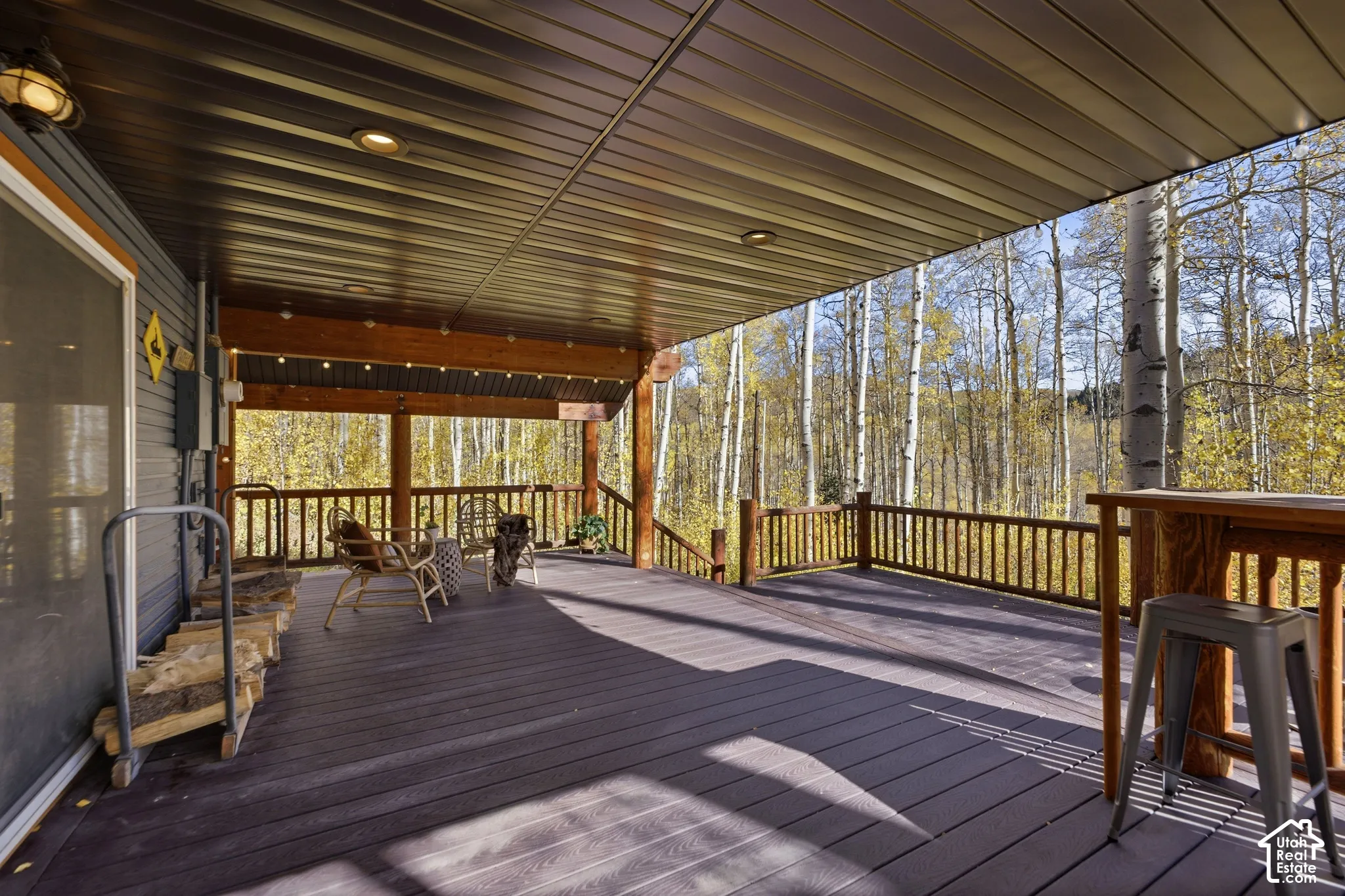 Covered deck featuring composite wood-finish decking, recessed lighting, and wooden post-and-rail balustrades