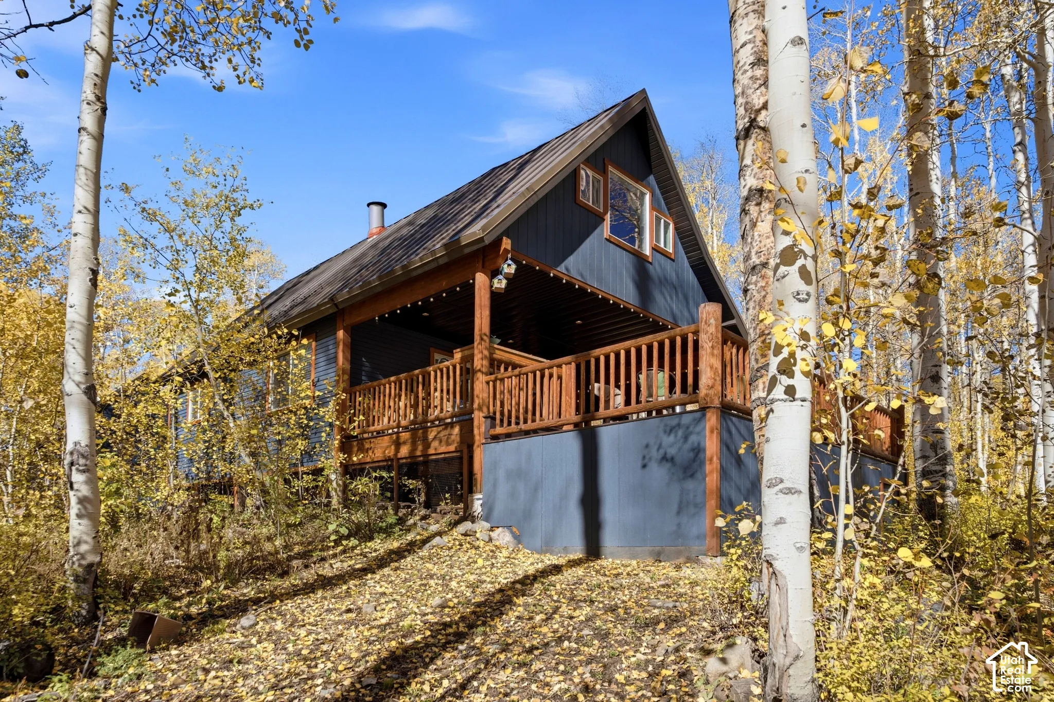 A-frame exterior featuring dark vertical siding, a metal roof, and a prominent wood-railed deck