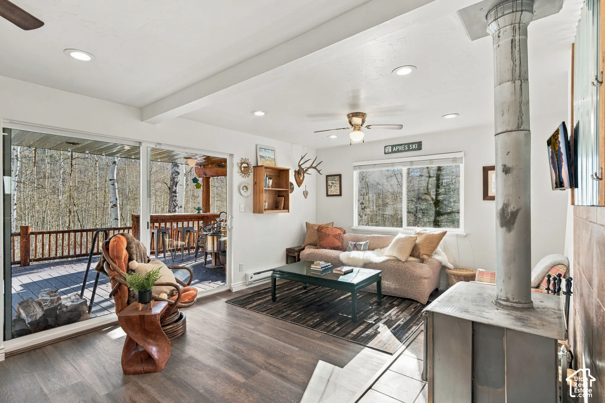Living space featuring wood-finish flooring, a freestanding metal fireplace, sliding glass doors, recessed lighting, and a ceiling fan
