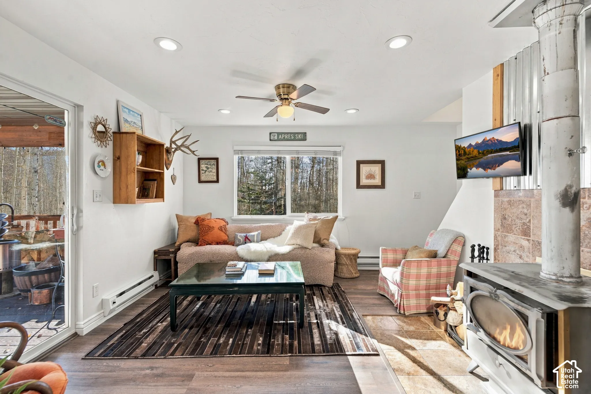 Living space featuring a freestanding wood-burning stove with a tiled hearth and corrugated metal surround, wood-finish flooring, recessed lighting, and sliding glass door access