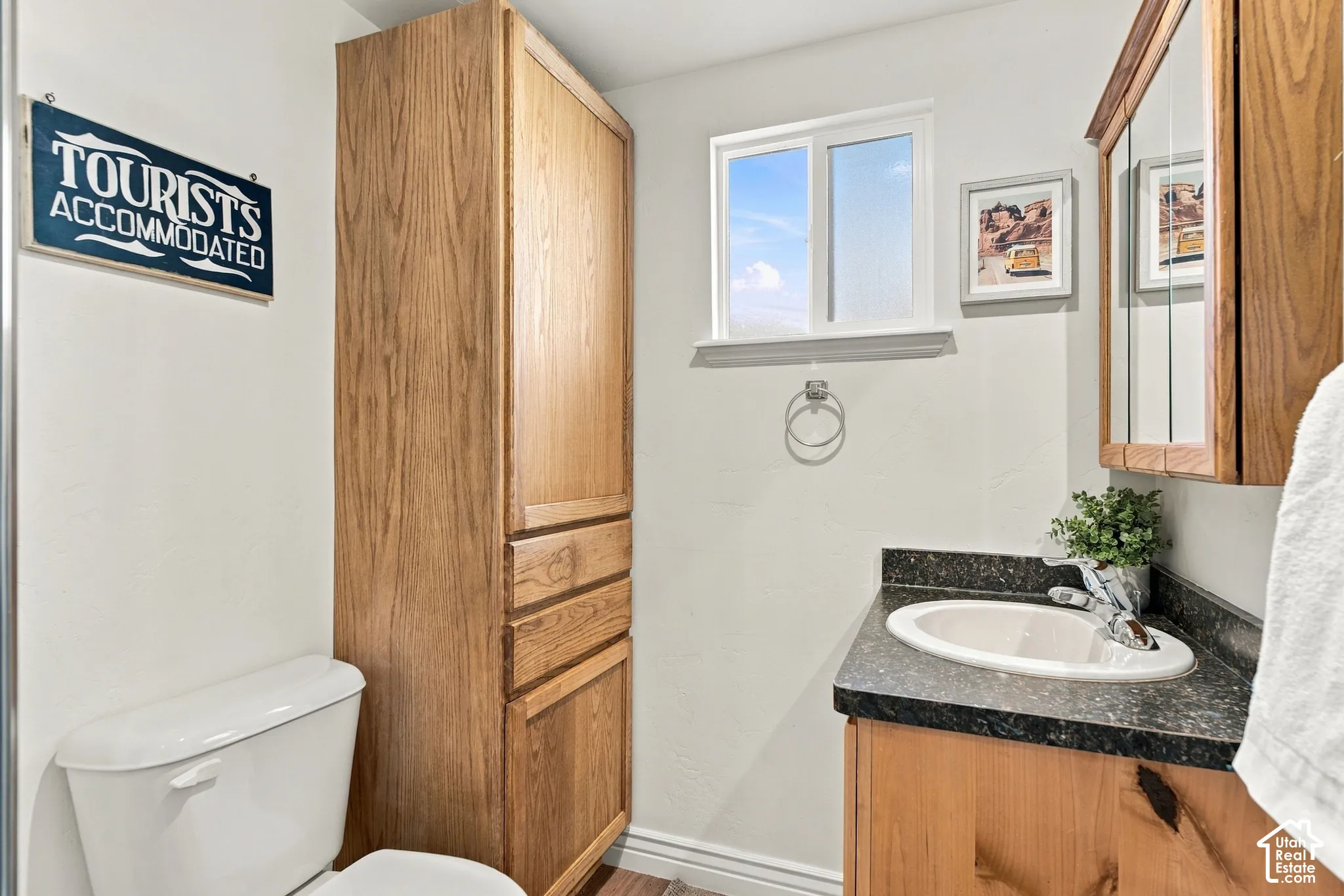 Wood-finish cabinetry, built-in floor-to-ceiling storage, vanity with stone-finish countertop, undermount sink, and medicine cabinet