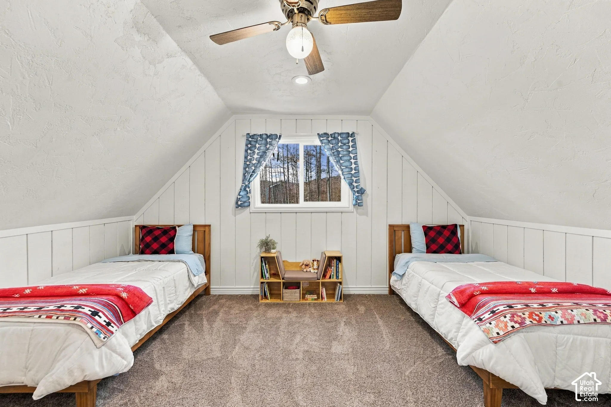 Vaulted ceiling featuring a central lighted ceiling fan, vertical wood-paneled walls, and carpeted flooring