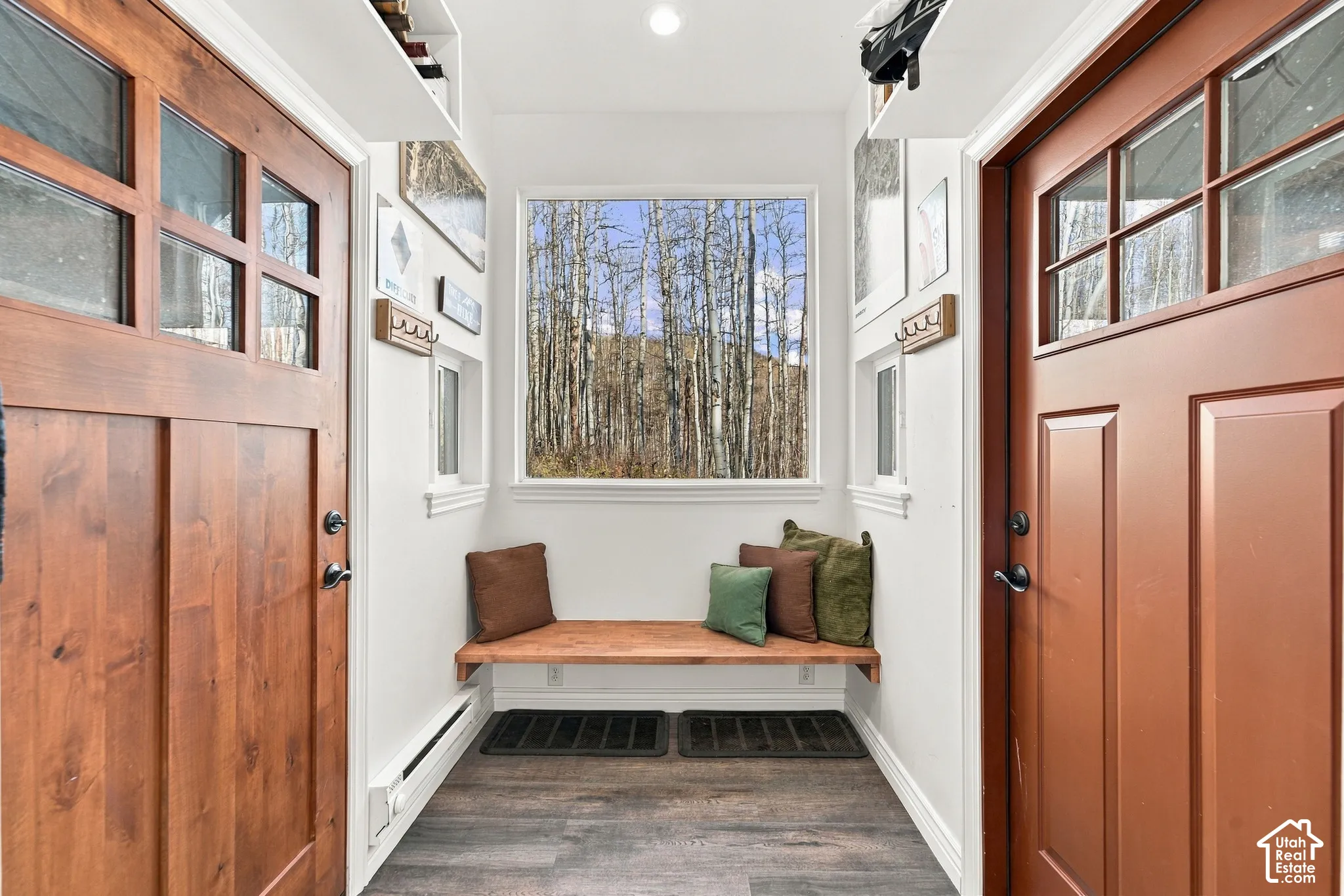 Entryway featuring two solid wood-paneled doors with glass inserts, wood-finish flooring, a built-in wood bench, and a large picture window