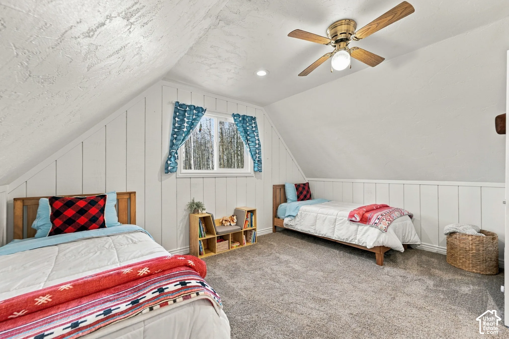 Vaulted ceiling, vertical plank wall paneling, wall-to-wall carpeting, and a ceiling fan with integrated lighting
