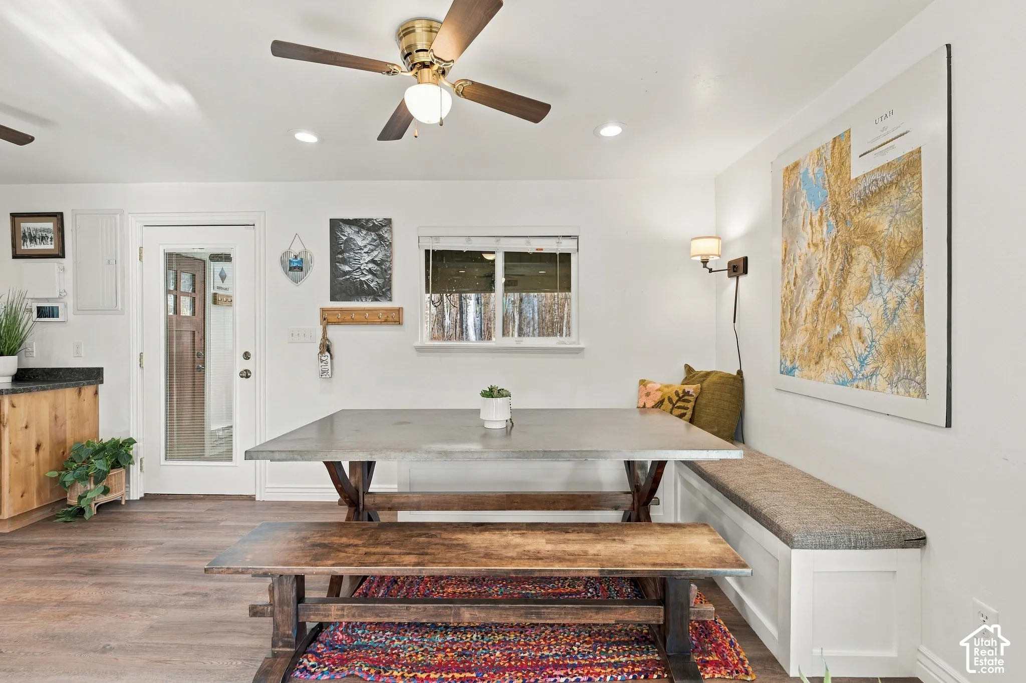 Built-in corner bench seating with white cabinetry, wood-finish flooring, ceiling fan with light fixture, and glass-paneled exterior door
