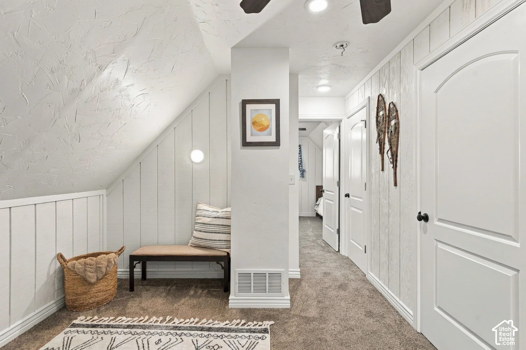 Interior hallway featuring vertical wood wall paneling, arched two-panel doors, recessed ceiling lighting, and a textured sloped ceiling