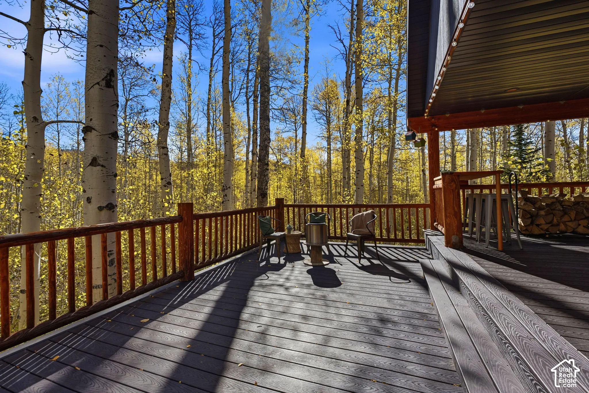 Expansive deck featuring dark composite decking, a rustic timber railing, and an integrated covered area