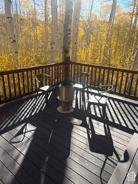 Raised deck with dark-toned composite decking, timber post-and-rail balustrades, and a forested backdrop