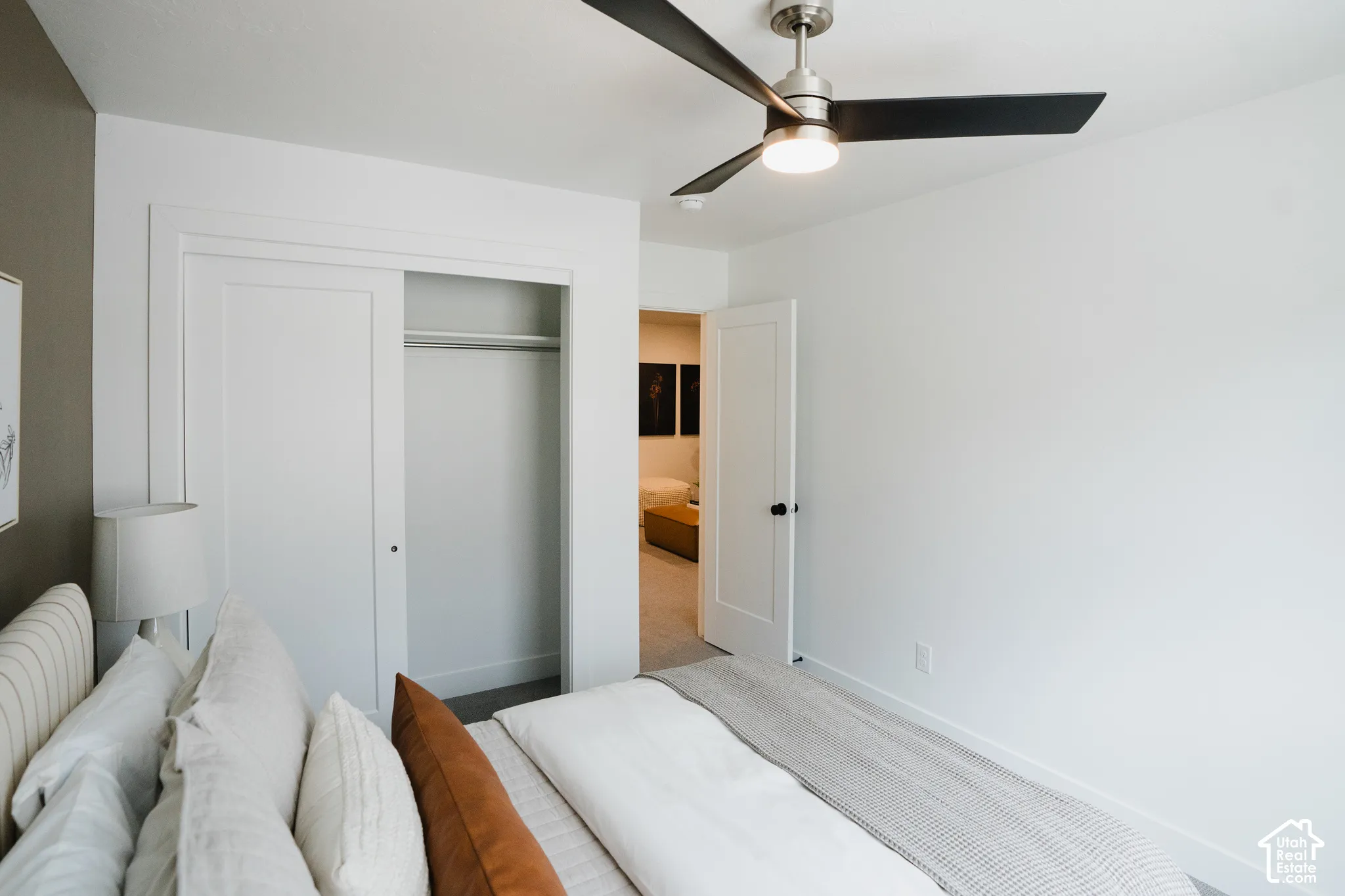 Bedroom featuring a brushed nickel ceiling fan with integrated lighting and built-in closet with sliding panel doors