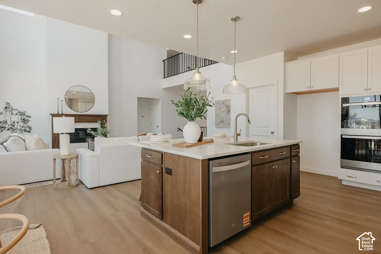 Kitchen island with stone-surface countertop, stainless steel appliances, wood-finish flooring, built-in double oven, and recessed lighting