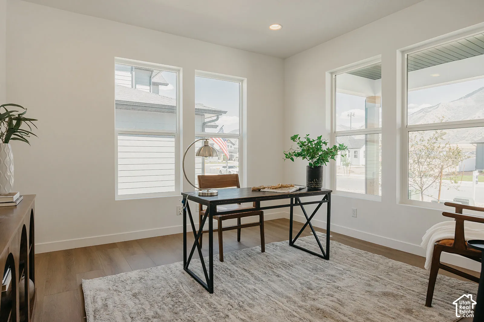 Neutral-toned room featuring wood-finish flooring, recessed lighting, and four large windows with mountain and neighborhood scenery