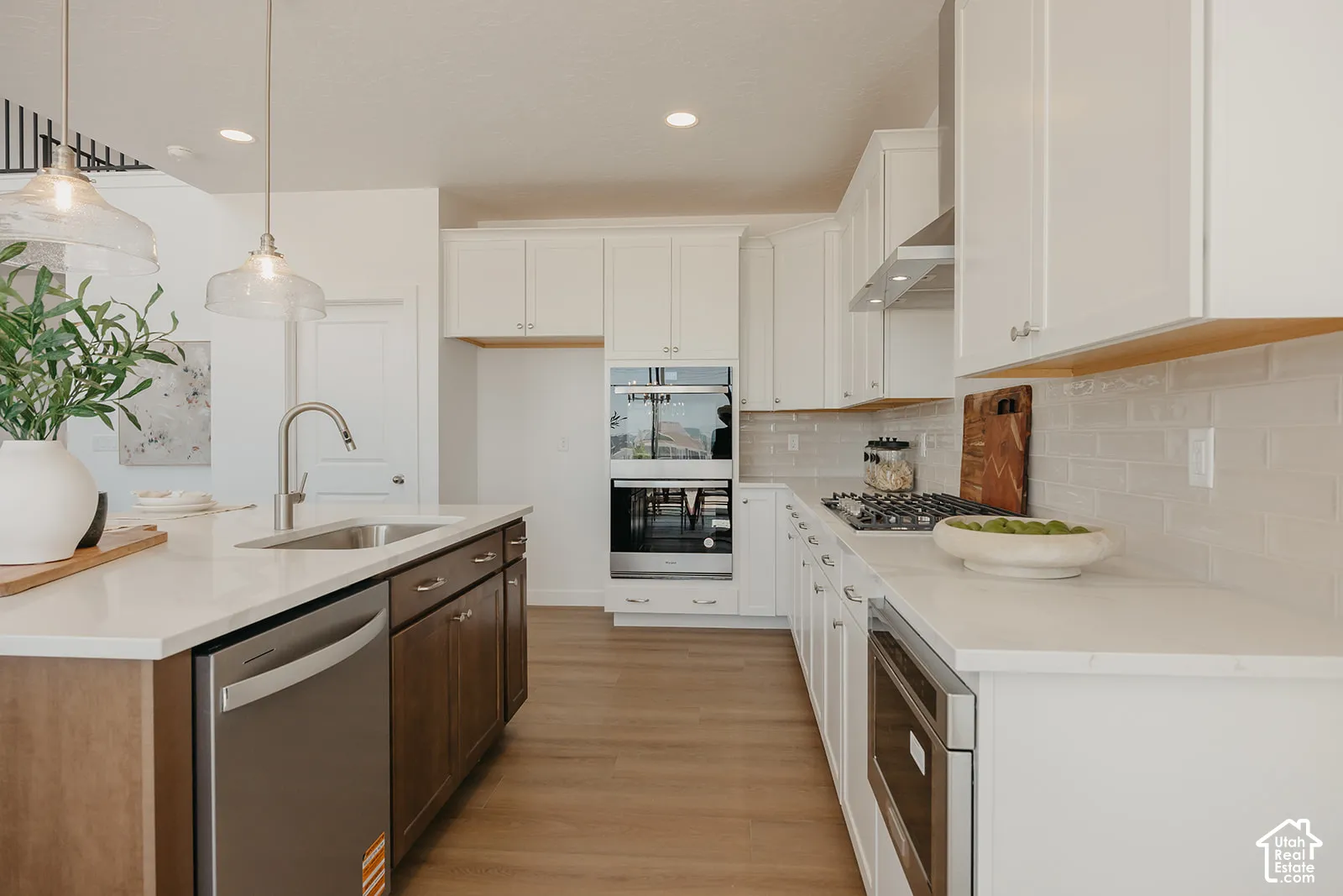 Kitchen featuring white cabinetry, wood-finish flooring, quartz countertops, a built-in double oven, and stainless steel appliances