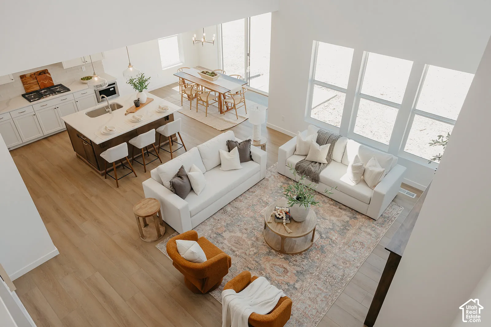 Open-concept layout with vaulted ceilings, large picture windows, wood-finish flooring, and a kitchen island with stone countertops